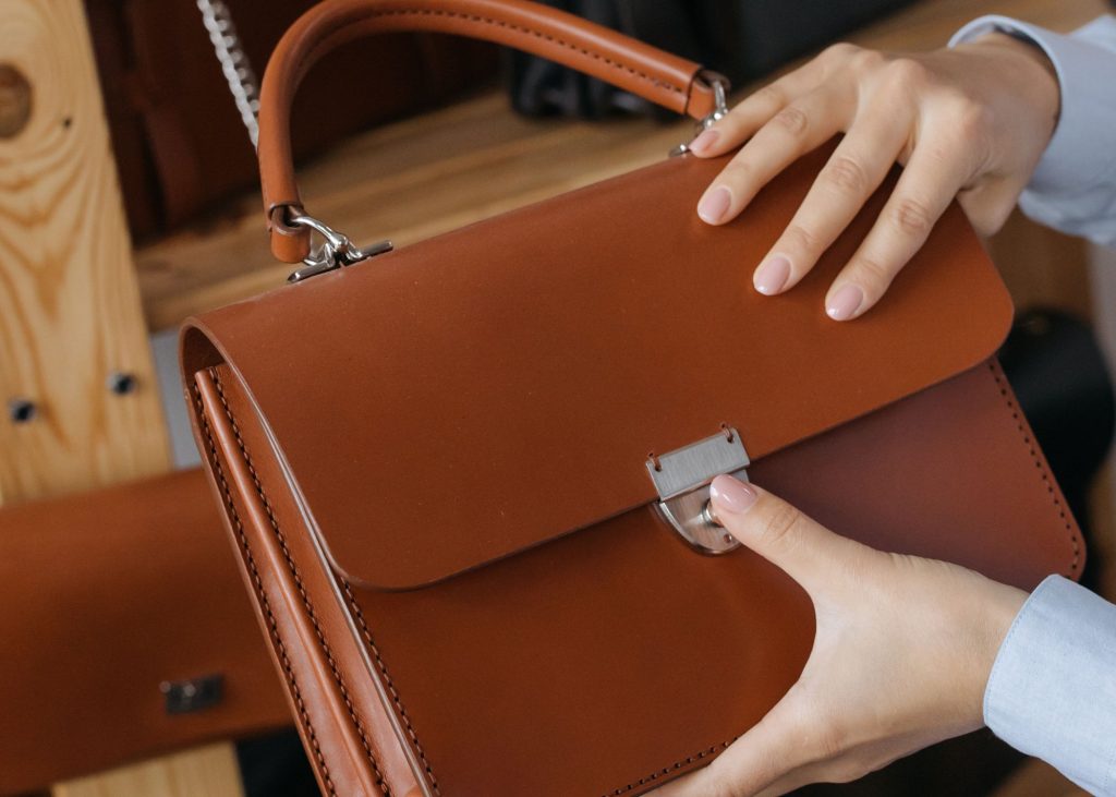 a hand holding a brown leather bag